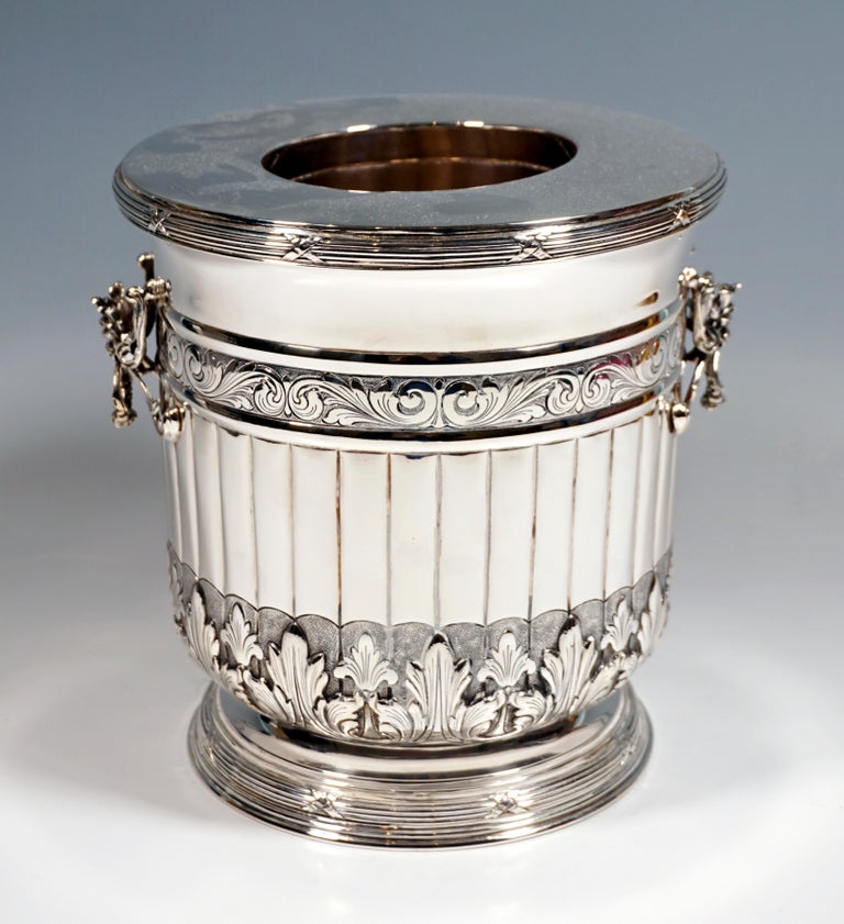 Richly decorated champagne or wine cooler:
Cylindrical vessel with a stepped, profiled, round base with cross band decoration and a slightly flared mouth rim, wall in the middle part with hump decoration, limited at the top by a chased volute