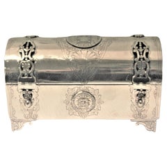 Silver chest-shaped jewelry box inlaid with monarchy coins and hinged lid