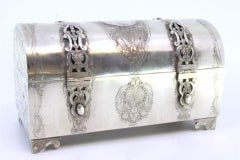 Silver chest-shaped jewelry box with coin appliqué and red velvet interior
