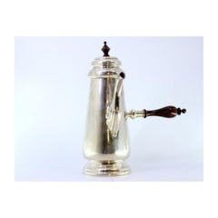 Silver chocolate maker with wooden handle and placed on a round base