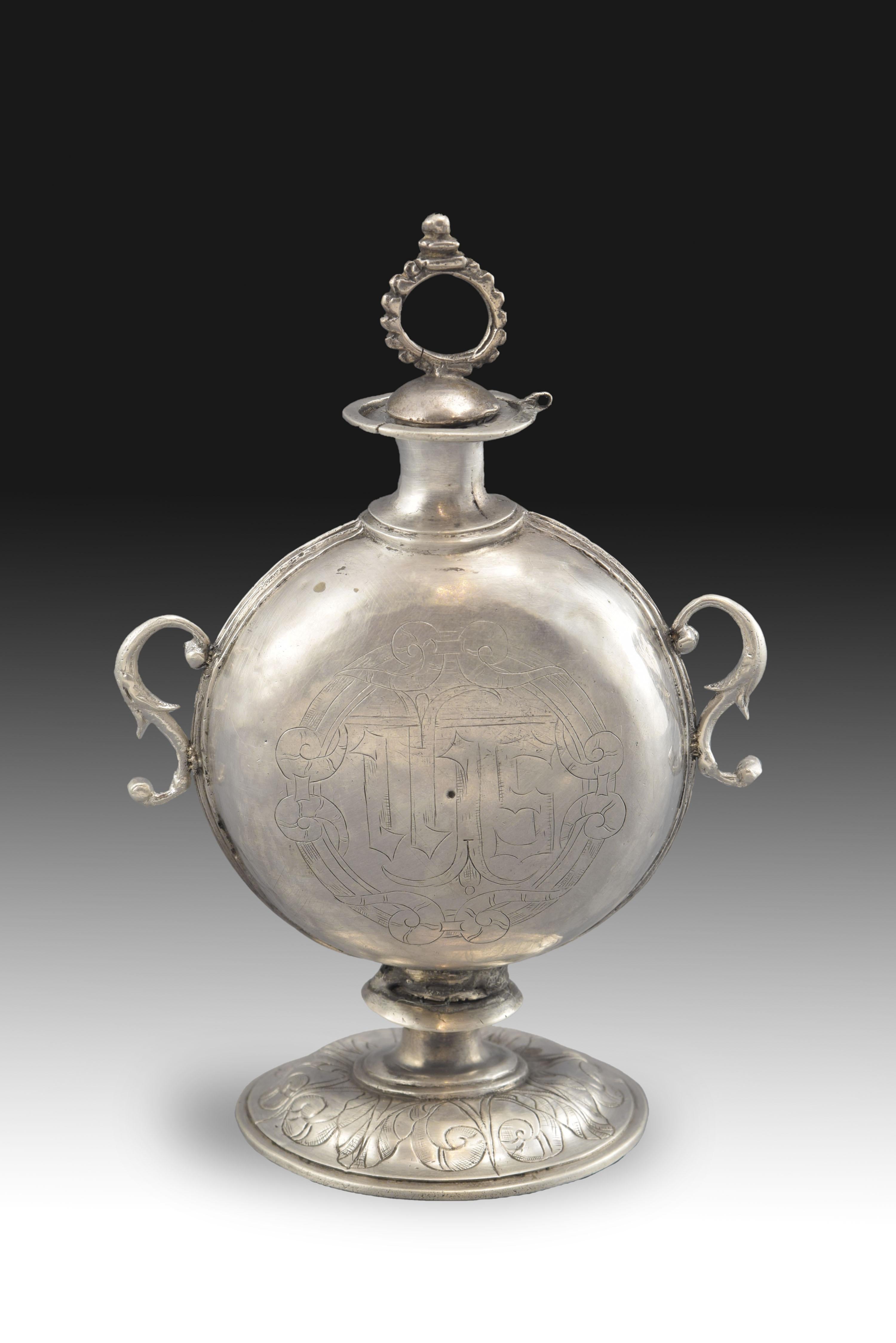 Crismera Silver in its color. 16th century. Cover not original.
Silver chrome in color with a circular foot decorated with an engraved composition of vegetable elements and a flat circular body with two 