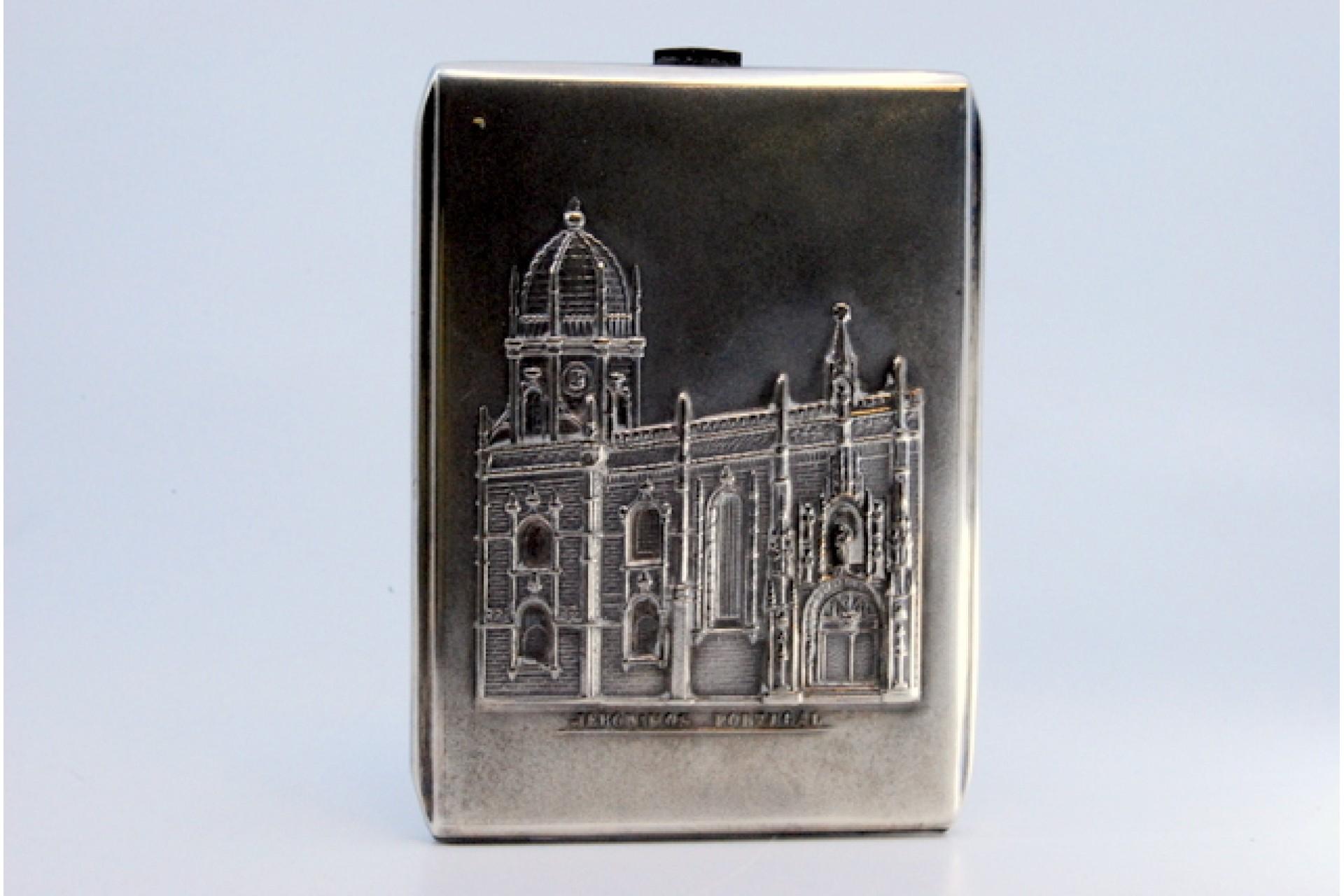 Description: Silver cigarette case with the Jerónimos Monastery in high relief, hinged lid. Metal: Silver. Origin: Portuguese. Mark: Eagle Head. Weight: 102.68 grams. Dimensions: 10.5x7.5cm. Content: 833/1000. Assay Mark: Yes, between 1938 and 1984.