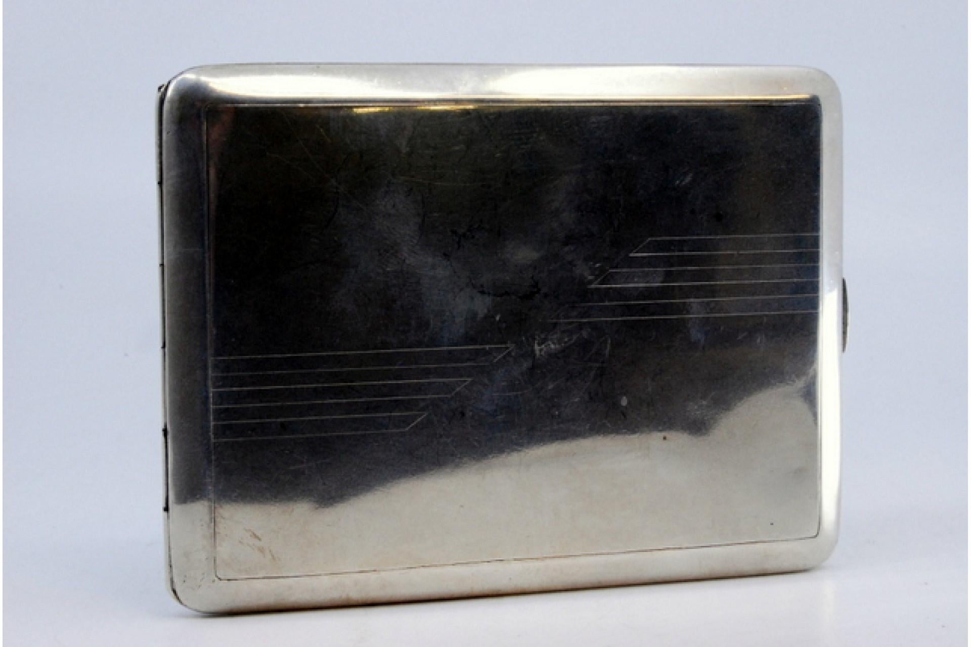 Description: Silver cigarette case with asymmetrical engraving, gold interior and hinged lid. Metal: Silver. Origin: Portuguese. Brand: Javali II Title. Weight: 128.68 grams. Dimensions: 11.5x8.5cm. Content: 833/1000. Assay Mark: Yes, between 1887