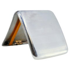 Silver cigarette case with bands on top, cigarette holder inside and hinged lid