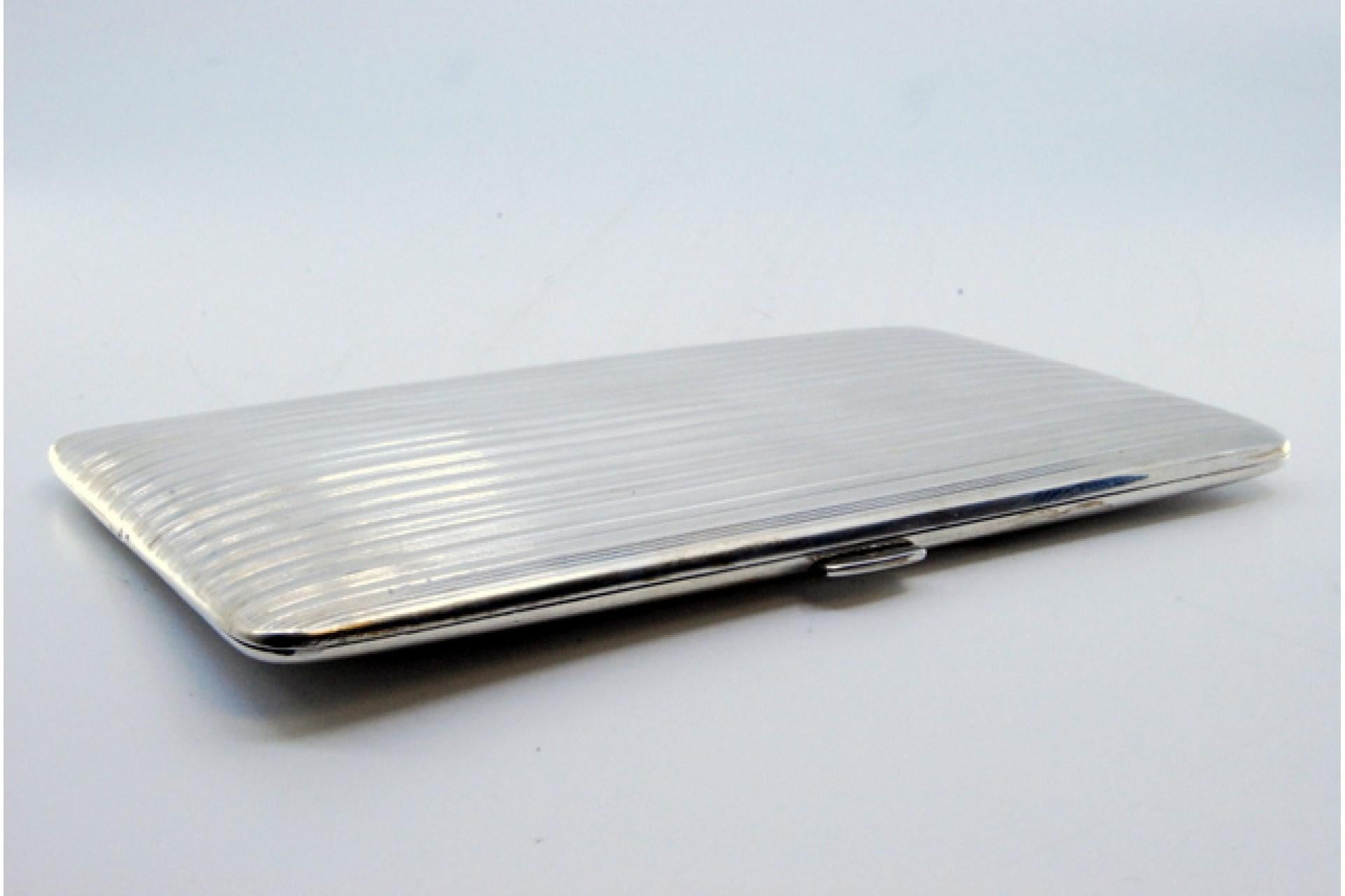 Description: Silver cigarette case with fluted bands on both sides and hinged lid. Metal: Silver. Origin: Portuguese. Brand: javali II Title. Weight: 191.65 grams. Dimensions: 14x8.1cm. Content: 833/1000. Assay Mark: Yes, between 1887 and 1937.