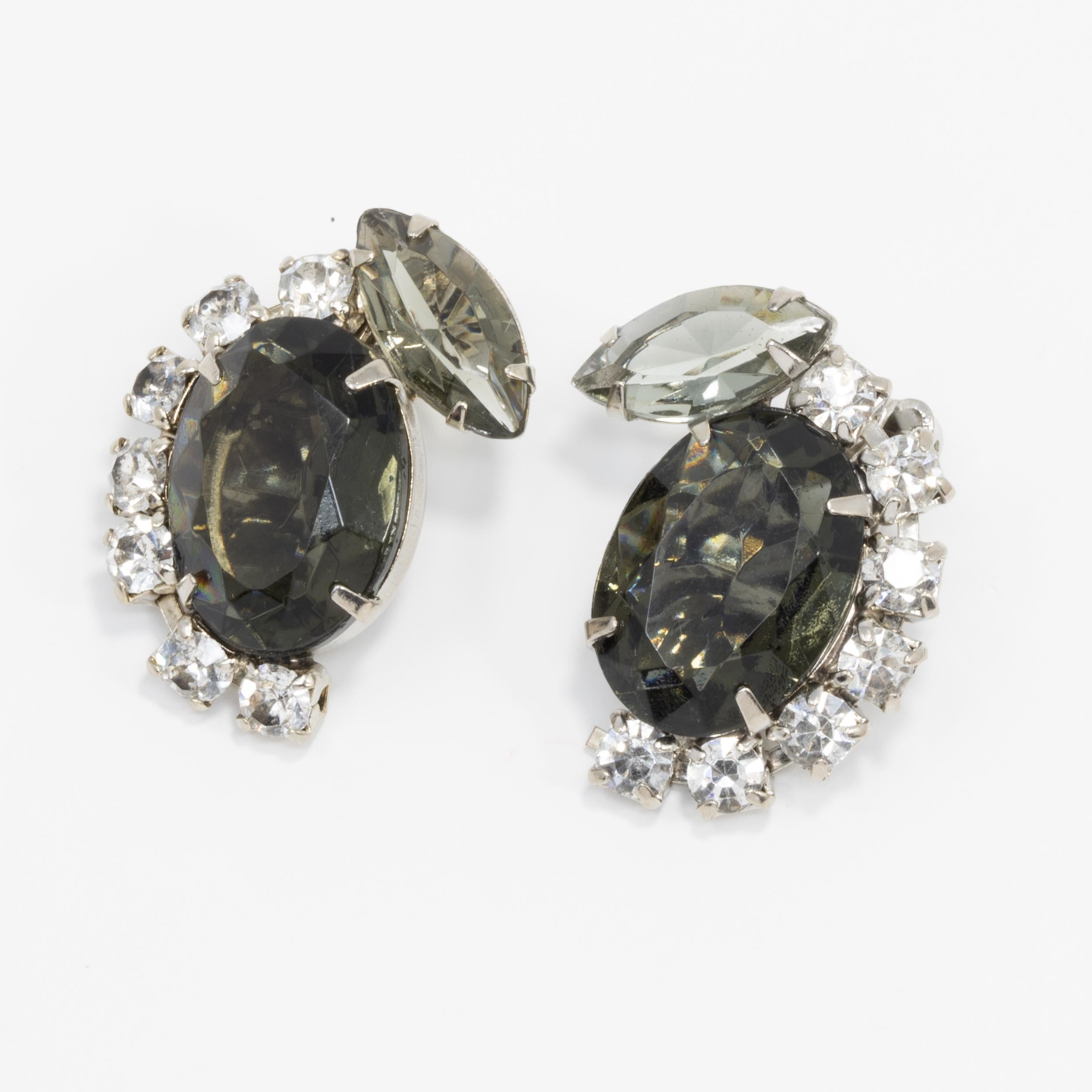A pair of retro clip on earrings, with large, centerpiece, smoky gray crystals, accented with prong-set, clear crystals. Silvertone.

Circa mid 1900s.