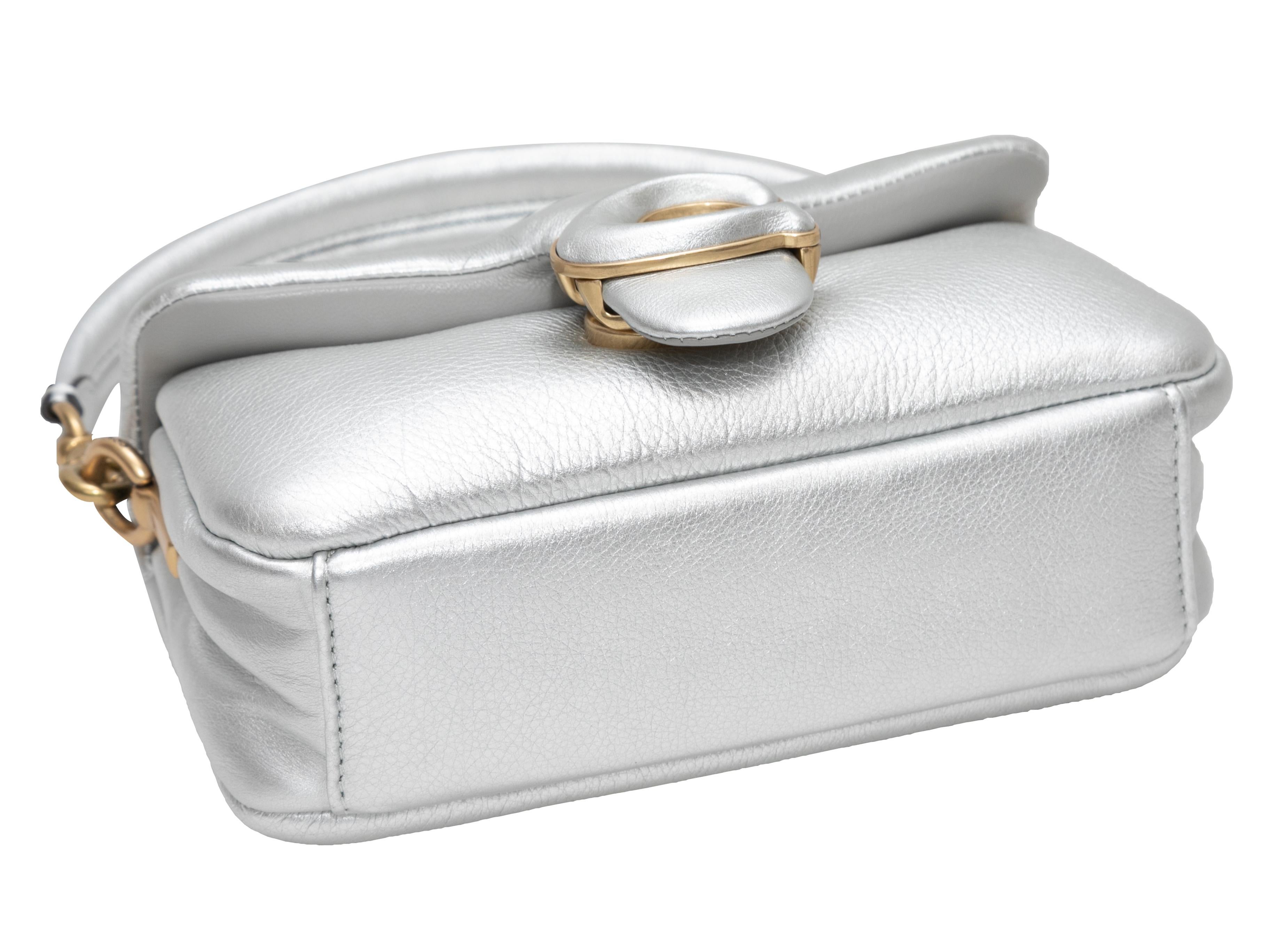 Silver Coach Pillow Tabby Purse. The Pillow Tabby Purse features a metallic leather body, gold-tone hardware, a single shoulder strap, an optional crossbody strap, and a front flap closure. 7.5