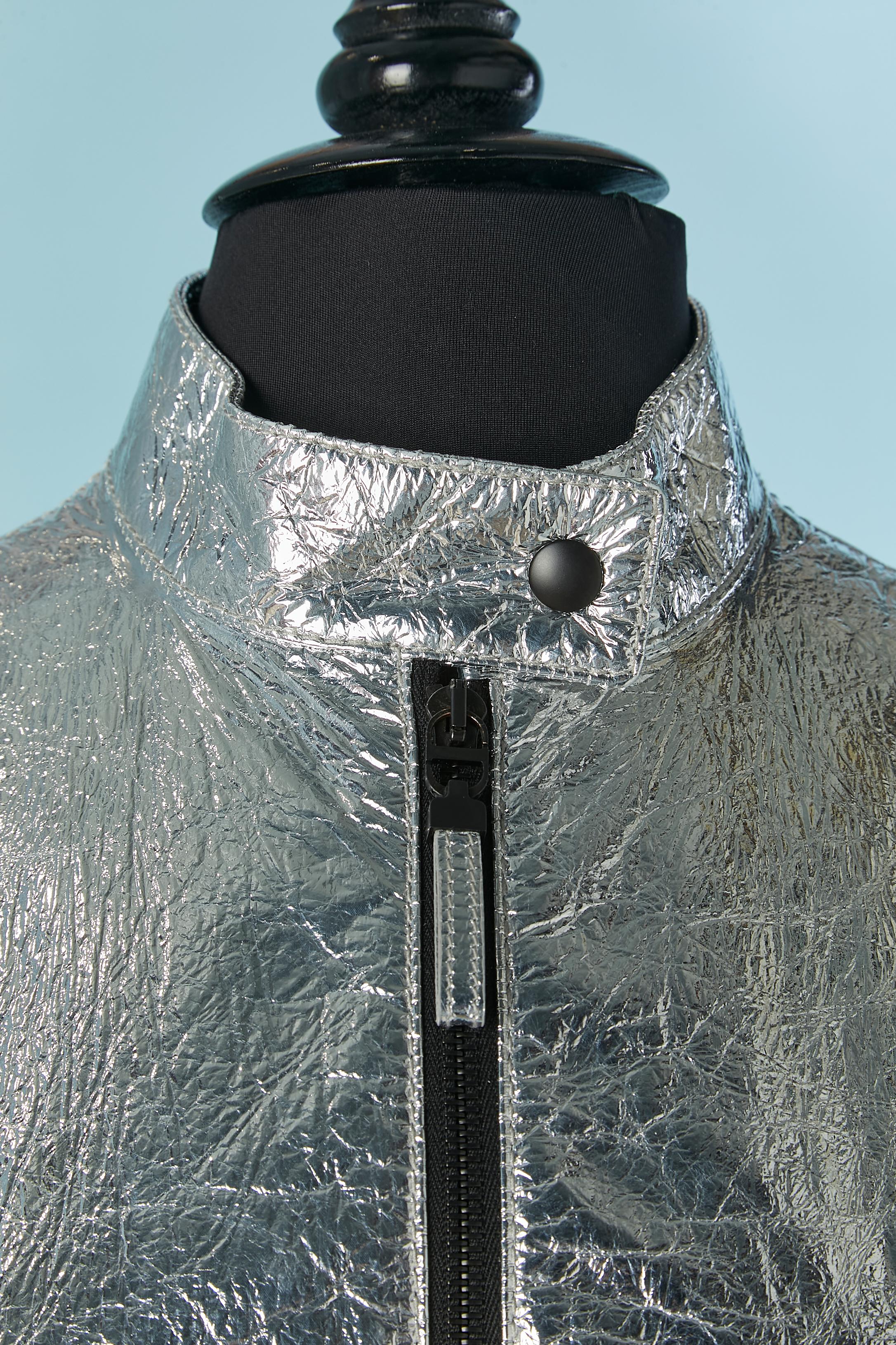 Silver coated leather jumpsuit. Rayon lining. Zip closure on the middle front with one snap on the collar. Belt with belt loop and buckle closure. Pocket on both side with zip closure. Zip and snap on the cuffs. Eyelet under the armpit. 
SIZE 38
