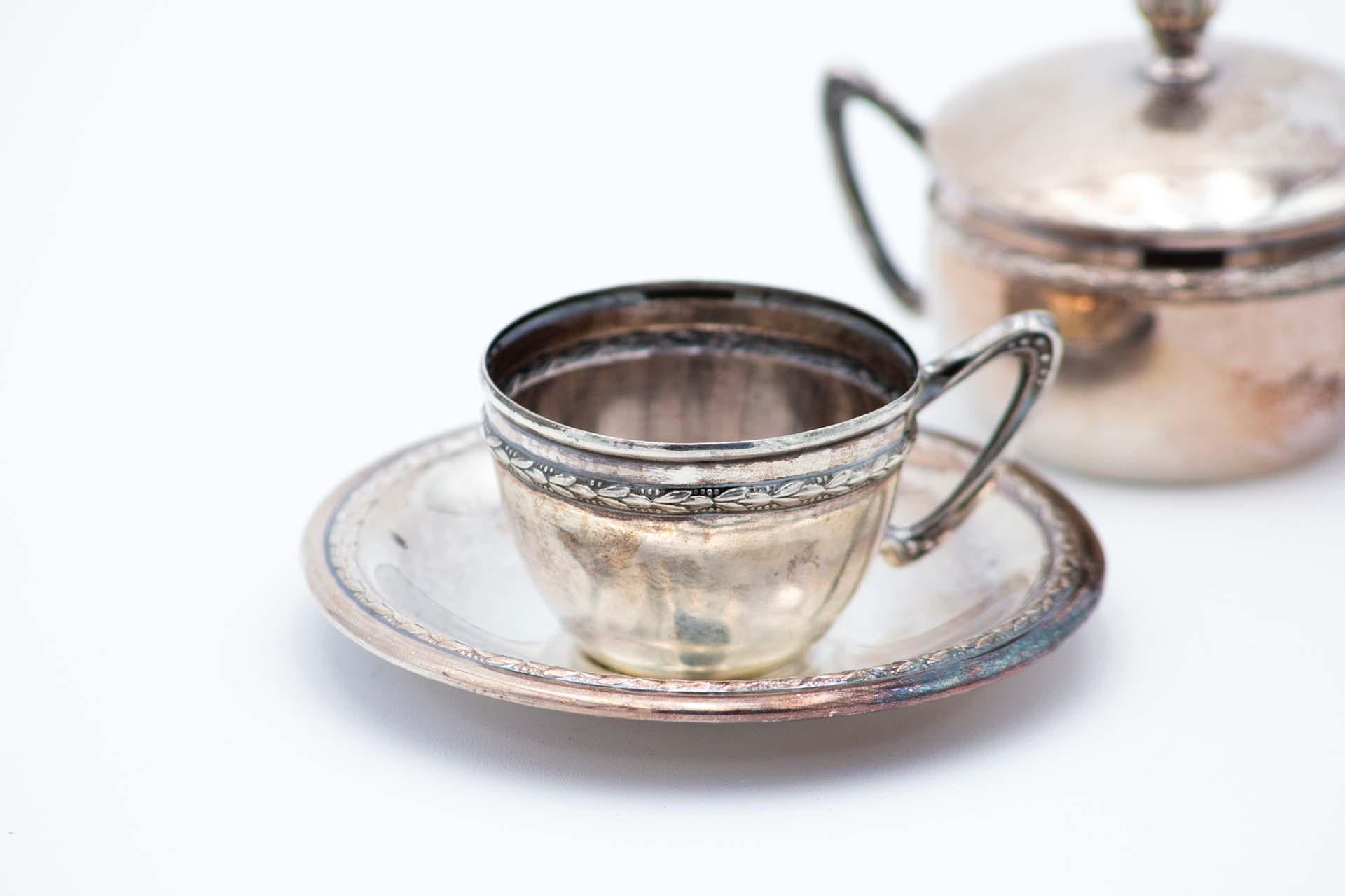 Description: Silver coffee cup, saucer, and sugar bowl set, with a knob on the removable lid and surrounding cold cuts. Metal: Silver. Origin: German. Brand: Unknown. Weight: 38.03 grams. Dimensions: Saucer 9.1cm x 1.2cm. Content: 800/1000. Assay