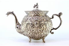 Silver coffee pot with embossed female and elf faces, claw-foot base