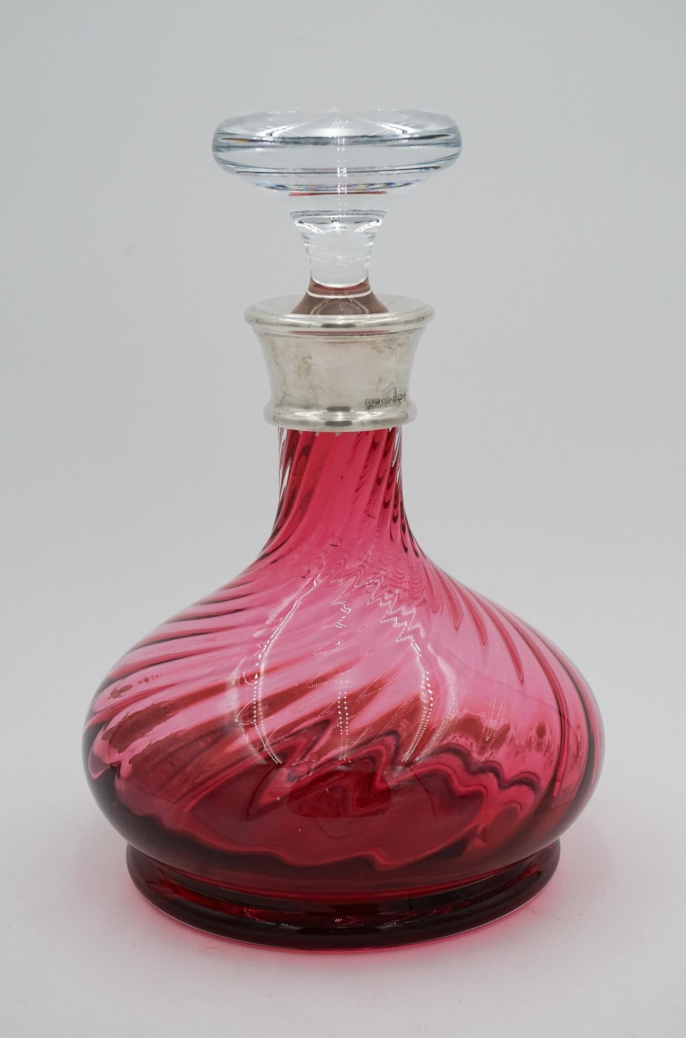 
The Silver Collared Hand Blown Cranberry Crystal Decanter from the Hardwicke Collection is a stunning piece that showcases exquisite craftsmanship. 

This decanter features a rich cranberry colour, achieved through the expert hand-blowing