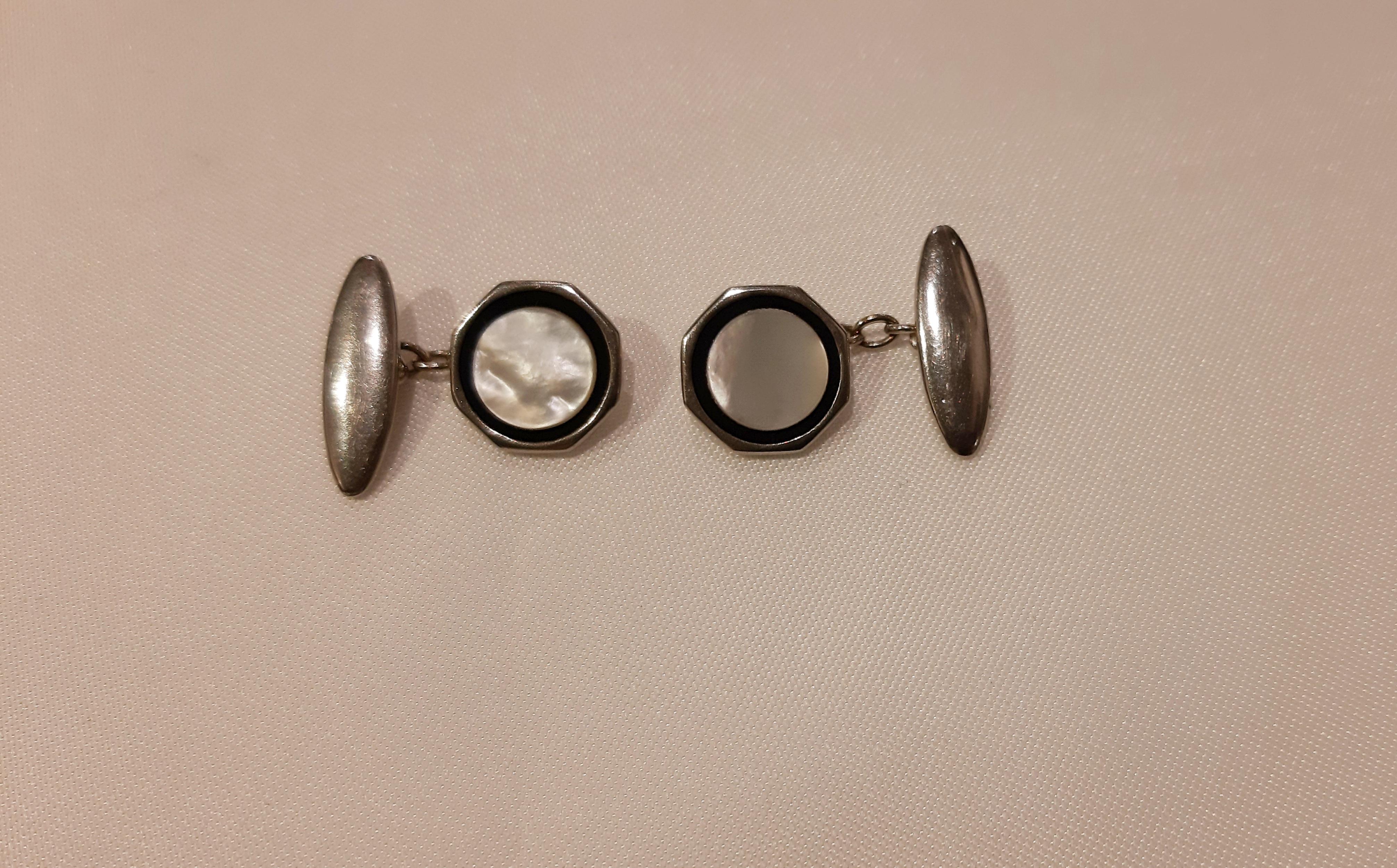 Silver-colored metal cufflinks with 1960s mother of pearl like with black enamel profile. 
Jewel of octagonal shape, each element is marked Lambournes from Birmingham with link chain to the suit. Lambournes was founded in 1955 as a supplier to the