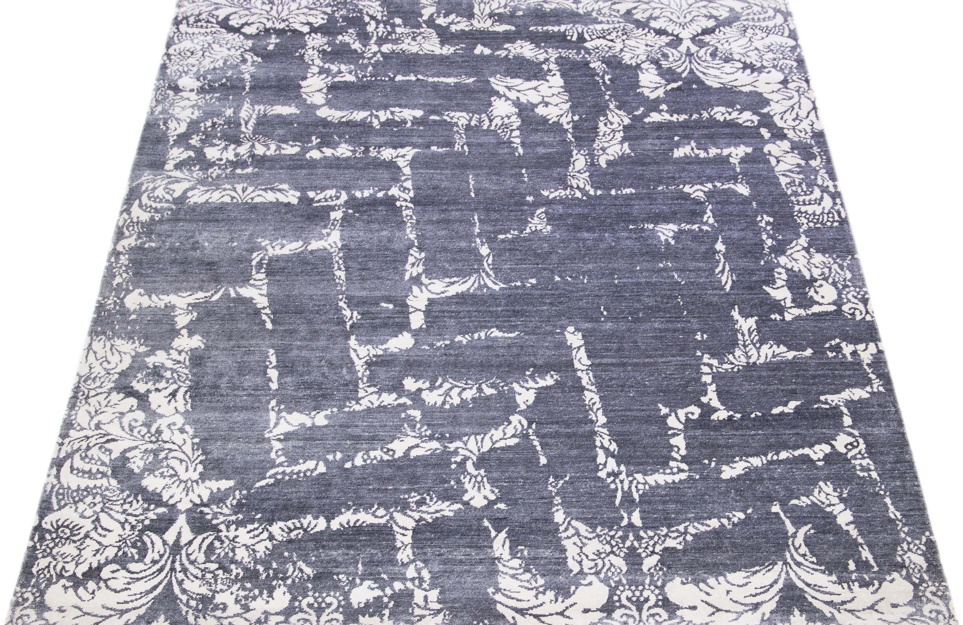 Questo tappeto indiano in misto lana e seta presenta un campo grigio/argento con un motivo astratto dai colori avorio. I materiali di cui è composto garantiscono robustezza e longevità, mentre il suo design ornamentale infonde raffinatezza a
