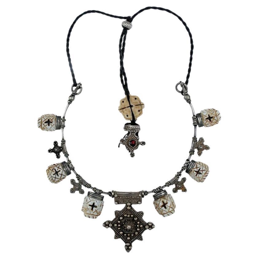 A Custom Made Necklace by Famous Moroccan Jeweler Chez Faouzi of Marrakech. Necklace is made of Antique Moroccan Silver and Conus Shell Charms with the Signature Faouzi Back Neck Charm. Black cord is adjustable to 35.