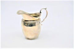 Silver creamer with twisted trim on the rim