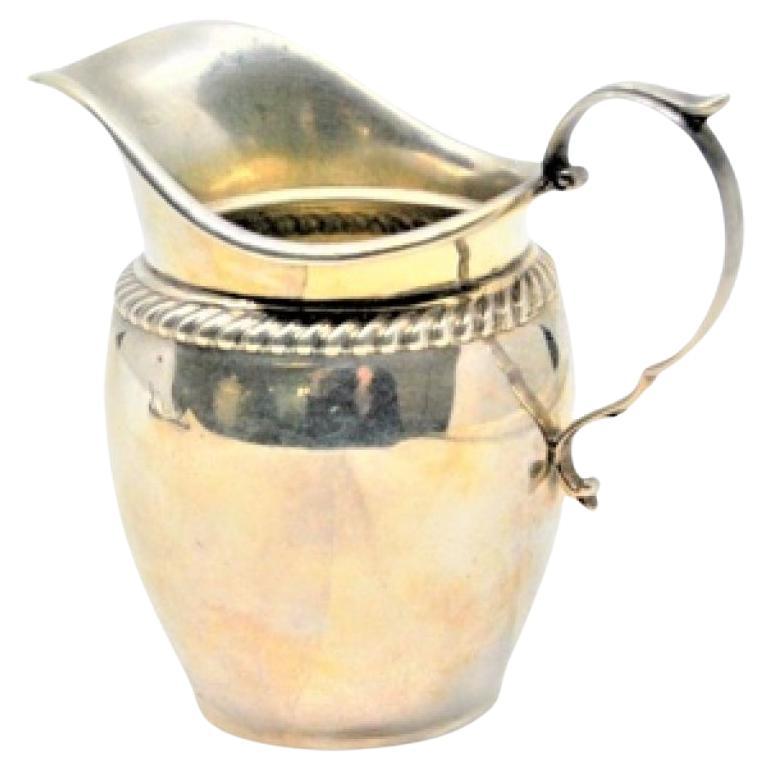 Silver creamer with twisted trim on the rim