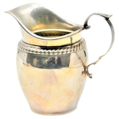 Silver creamer with twisted trim on the rim