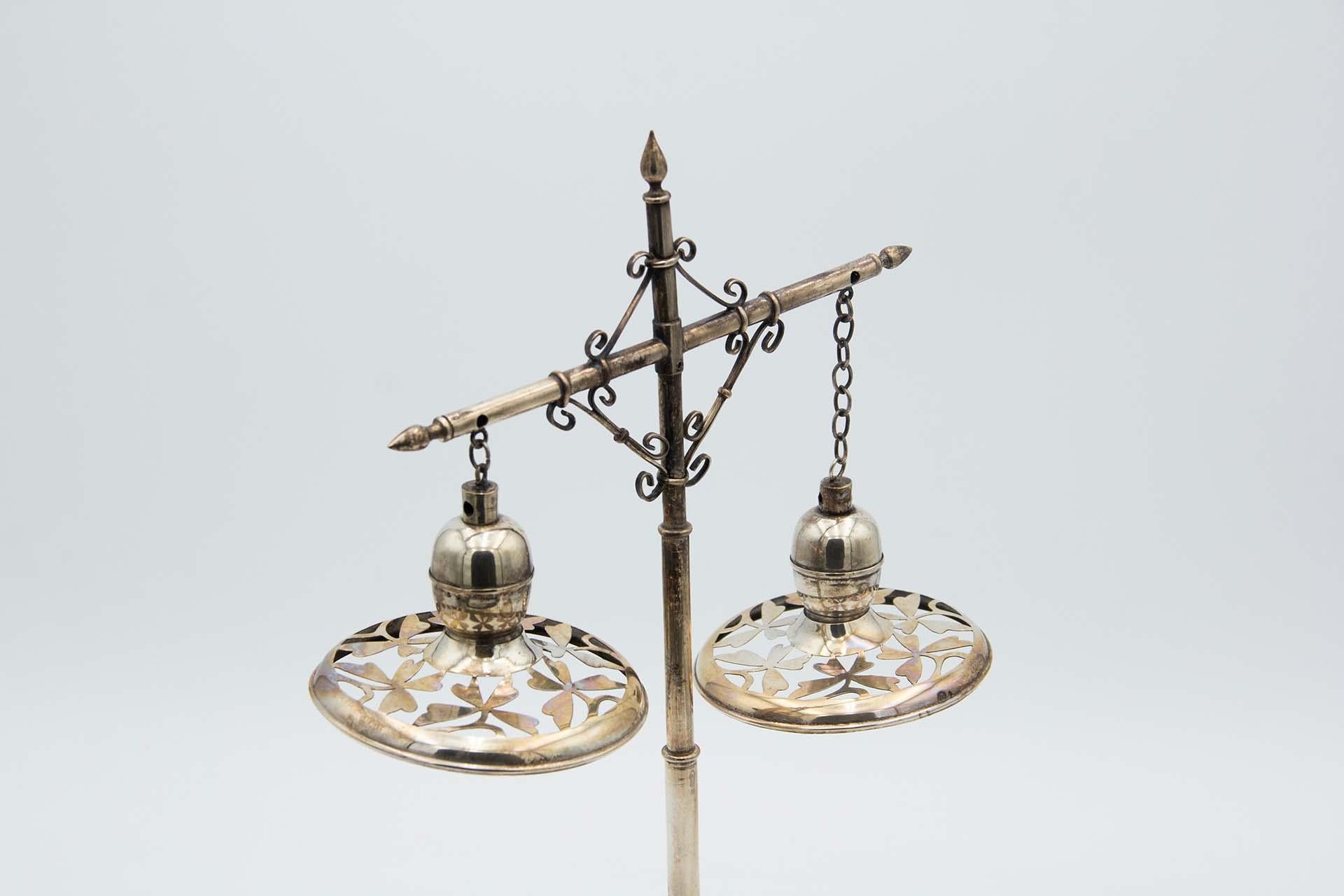 Description: Silver crucifix-shaped lamp with cut-out and suspended lampshades, smooth elliptical base. Metal: Silver. Origin: Portuguese. Brand: Javali II Title. Weight: 546.45 grams. Dimensions: 19.5cmx39.8cm. Content: 833/1000. Assay Mark: Yes,