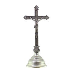 Silver crucifix with reliefs, resting on a plinth with friezes around it