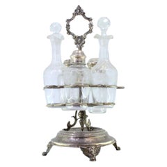 Vinagrera de plata engastada con vasos pulidos y base de tres patas con máscaras