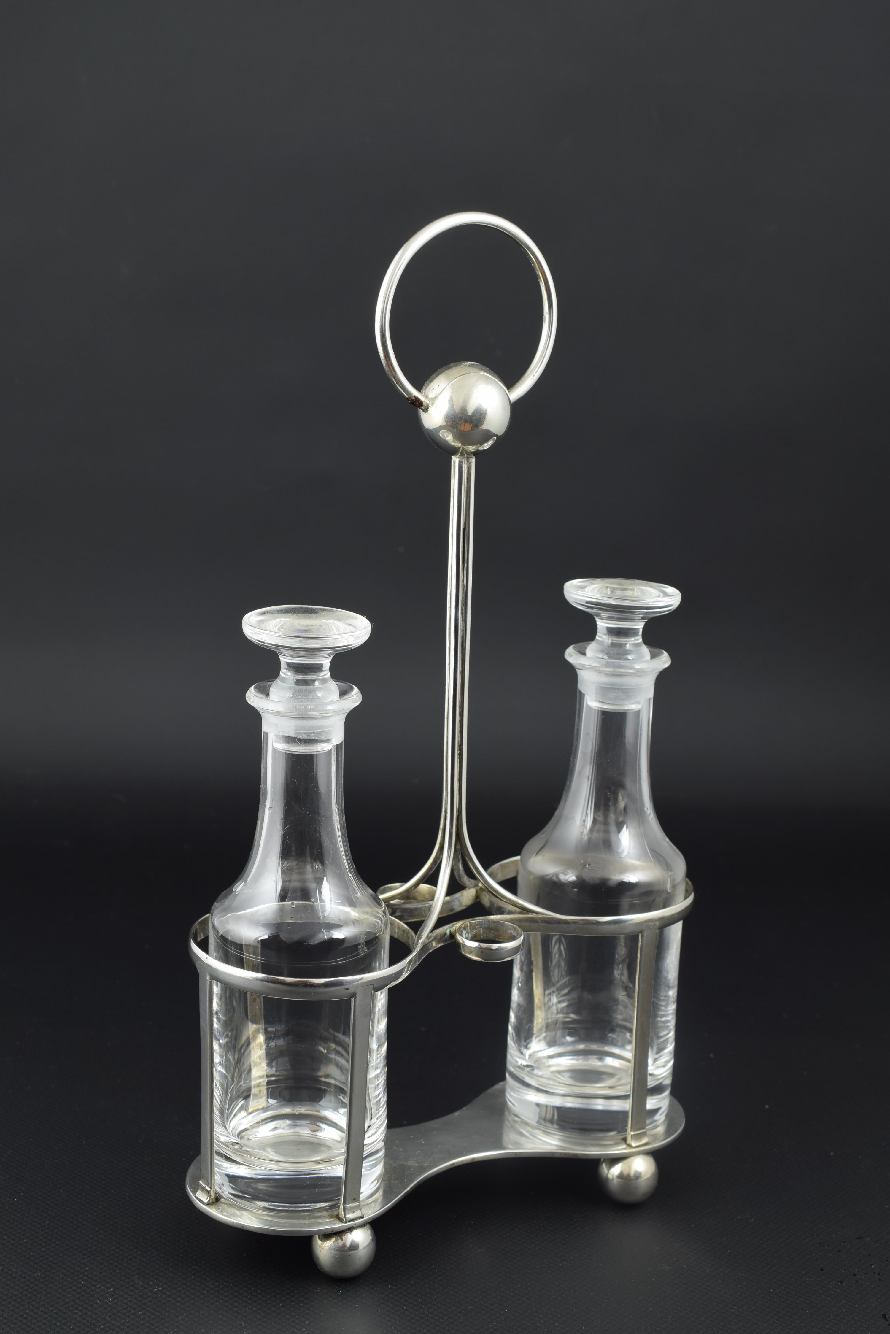 Cruet Convoy. Contrast by García Calvo, Valladolid, 1900.
With contrast marks. Glass and silver.
Silver convoy formed by a base on large pearls and with a central axis topped by a ring and another ball.
The simplicity of lines brings the work