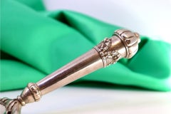 Silver crumb catcher with floral reliefs and bows on the handle