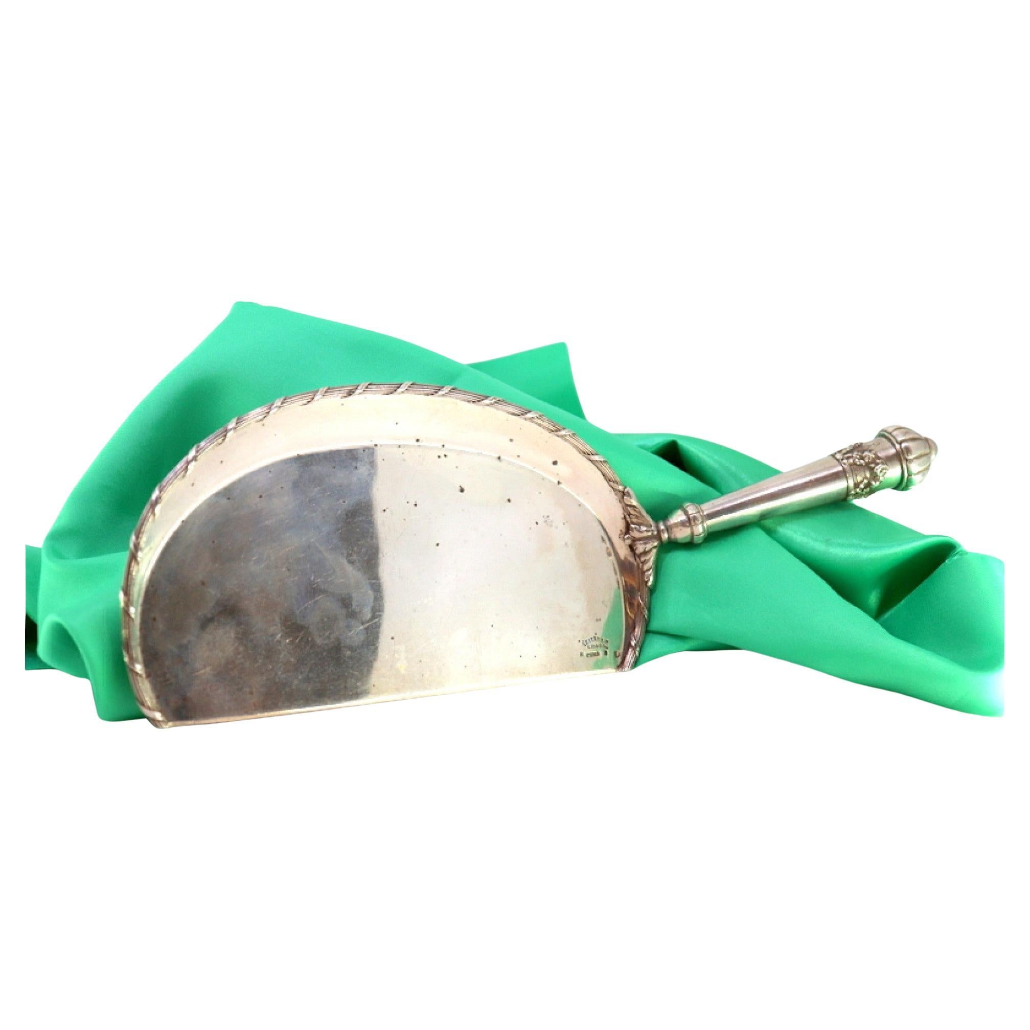 Silver crumb catcher with floral reliefs and bows on the handle