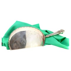 Silver crumb catcher with floral reliefs and bows on the handle