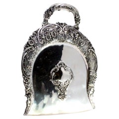 Ramasse-miettes en argent avec motifs floraux révélés entourant la carte du monogramme.