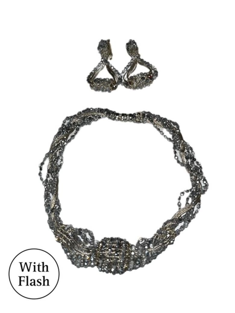 Arricchisci il tuo ensemble con questo splendido set di collana e orecchini a clip firmato Daniel Swarovski. Caratterizzata da un intricato disegno di fili e perline in argento metallico intrecciati tra loro, la collana è impreziosita da un grappolo