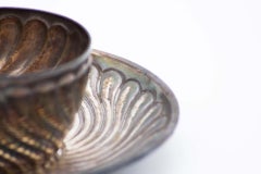 Silver cup and saucer with concentric reliefs