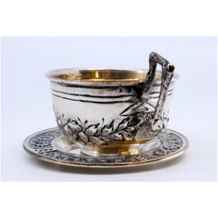 Silver cup and saucer with embossed floral motifs and appliquéd handle
