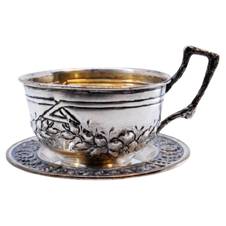 Silver cup and saucer with embossed floral motifs and appliquéd handle For Sale