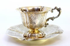 Silver cup and saucer with engraved floral motifs and cutouts on the edges