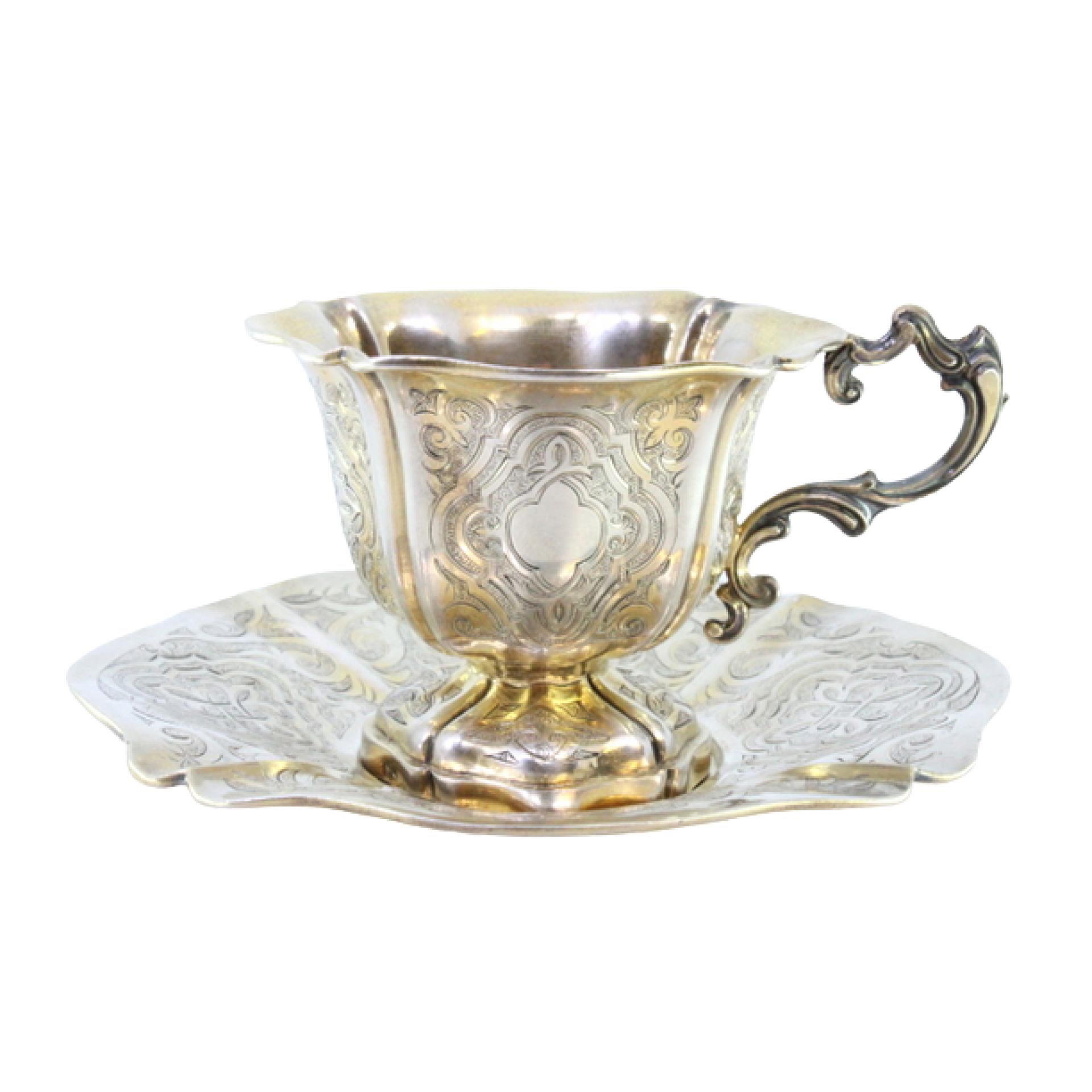 Silver cup and saucer with engraved floral motifs and cutouts on the edges
