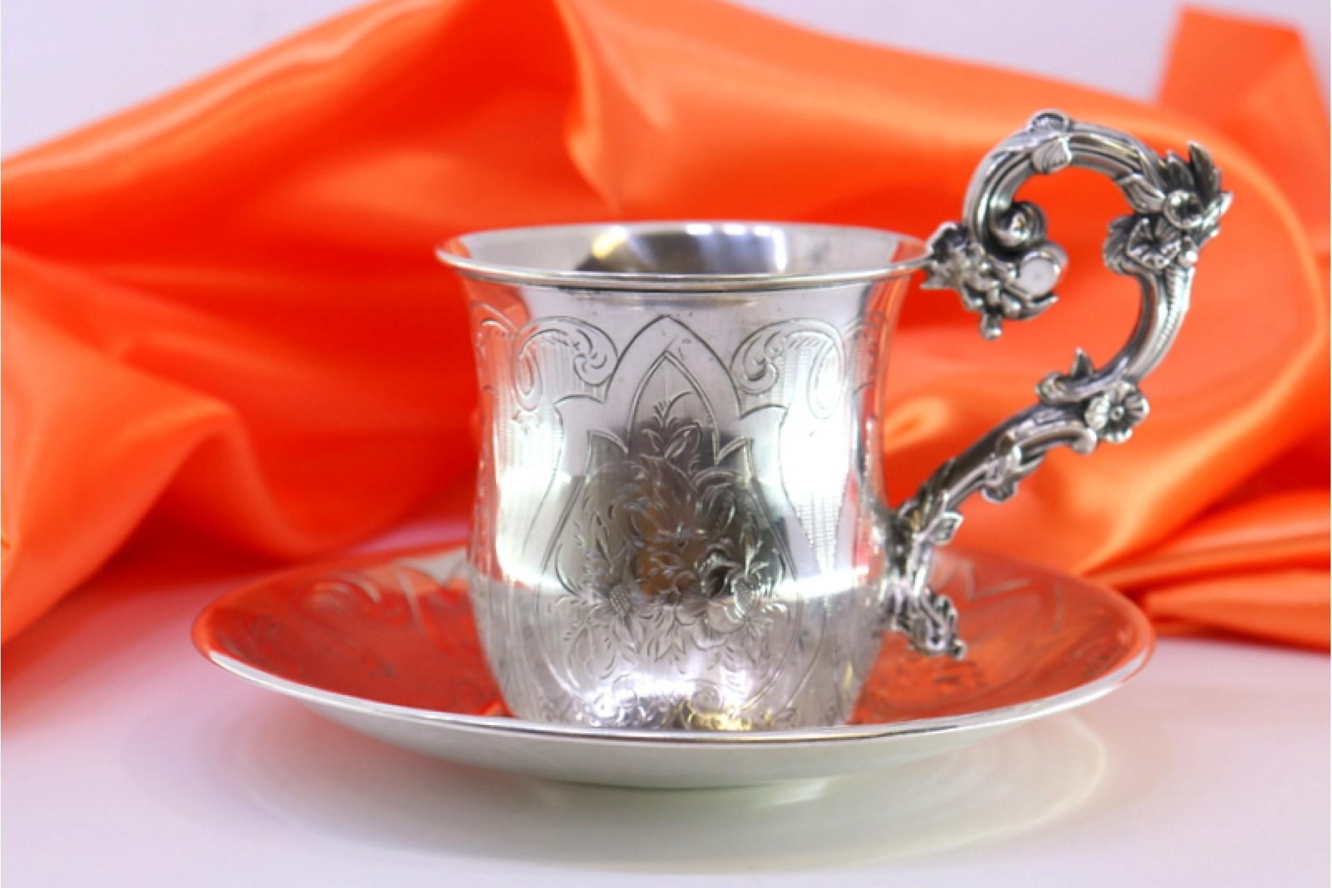 Description: Silver cup and saucer with engraved floral motifs and raised applications on the handle. Metal: Silver. Origin: French. Brand: Tête Minerve. Weight: 187.99 grams. Dimensions: Saucer - 14.5x14.5cm Cup - 11.5x9.5cm. Content: 950/1000.