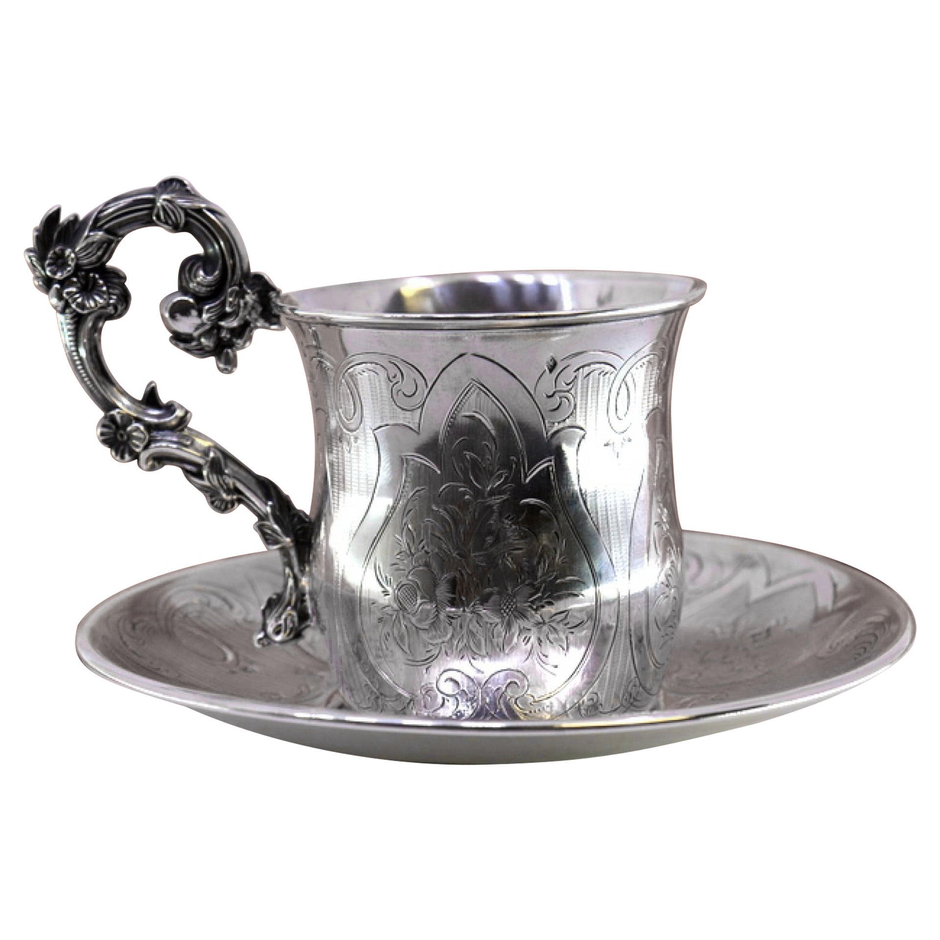 Silver cup and saucer with floral engravings and raised handle details