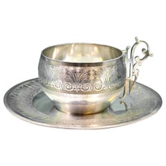 Silver cup and saucer with reliefs and cutouts on the handles