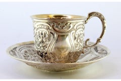Silver cup and saucer with reliefs and gold interior
