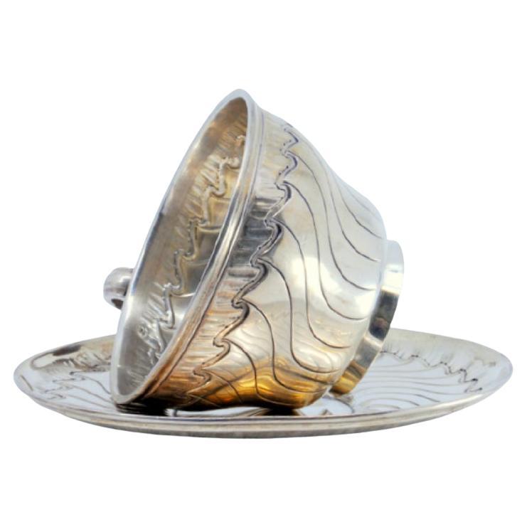 Silver cup and saucer with wavy engravings and friezes around the edges For Sale