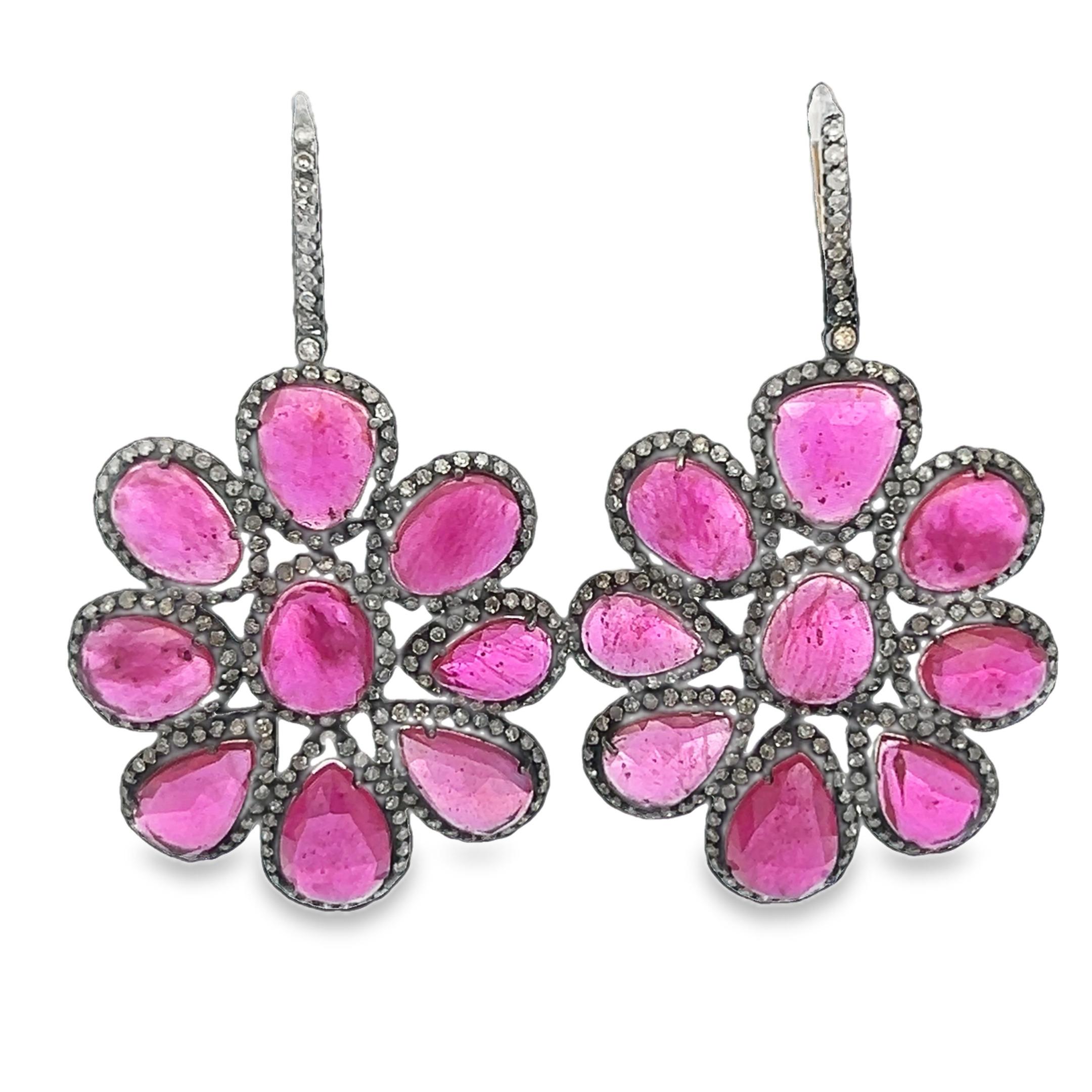 Setzen Sie ein Zeichen mit unseren silbernen Blumenohrringen mit Rubinen und Diamanten - ein wirklich einzigartiges und außergewöhnliches Design. Aus schimmerndem Silber gefertigt, formt jeder Ohrring eine zarte Blüte, in deren Mitte sich ein Rubin
