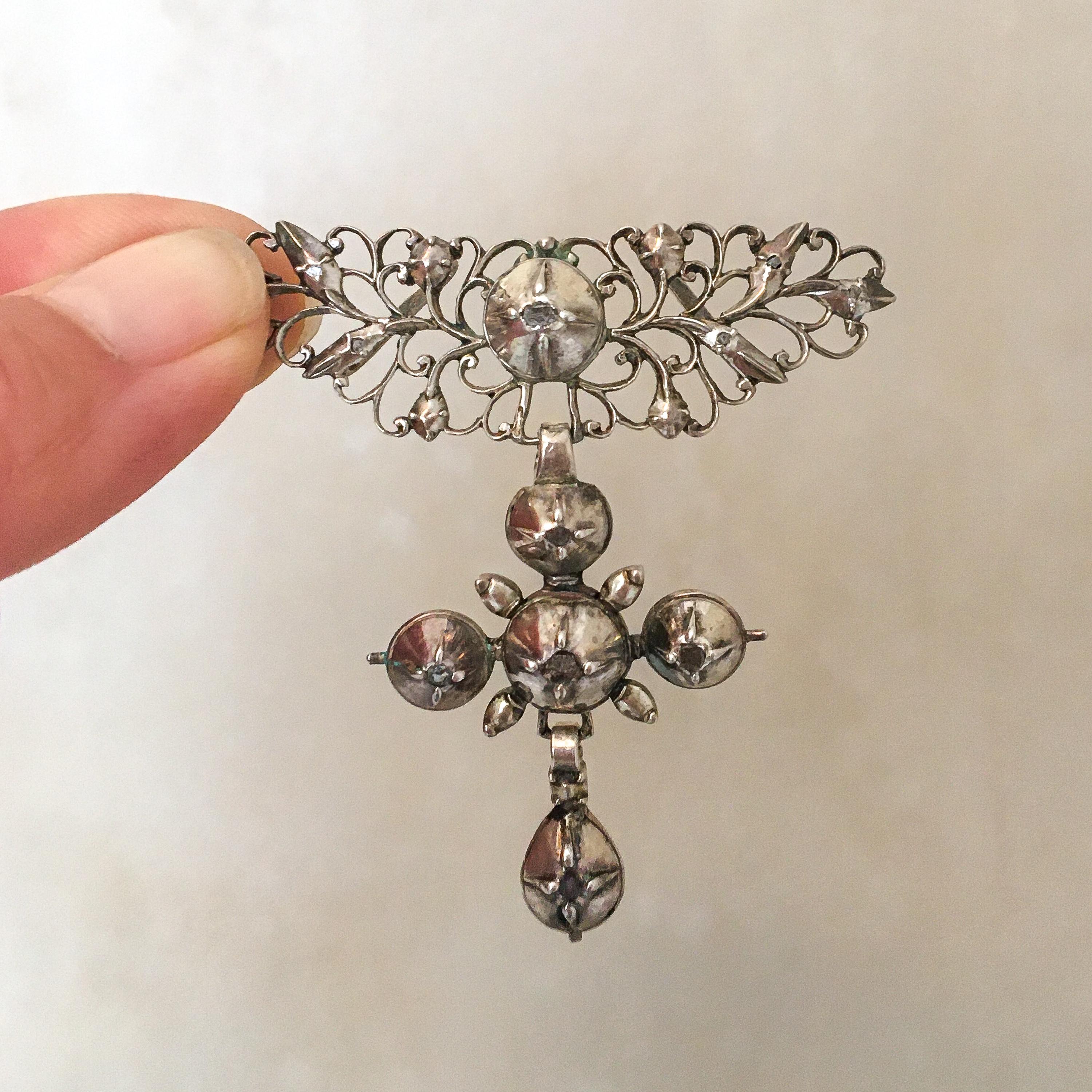 This is an antique early 19th century silver triple drop panel filigree cross pendant. The three graduated silver panels of open scrollwork are set with rose-cut diamonds in dome-shaped frames. Below the upper panel of the pendant you can see the