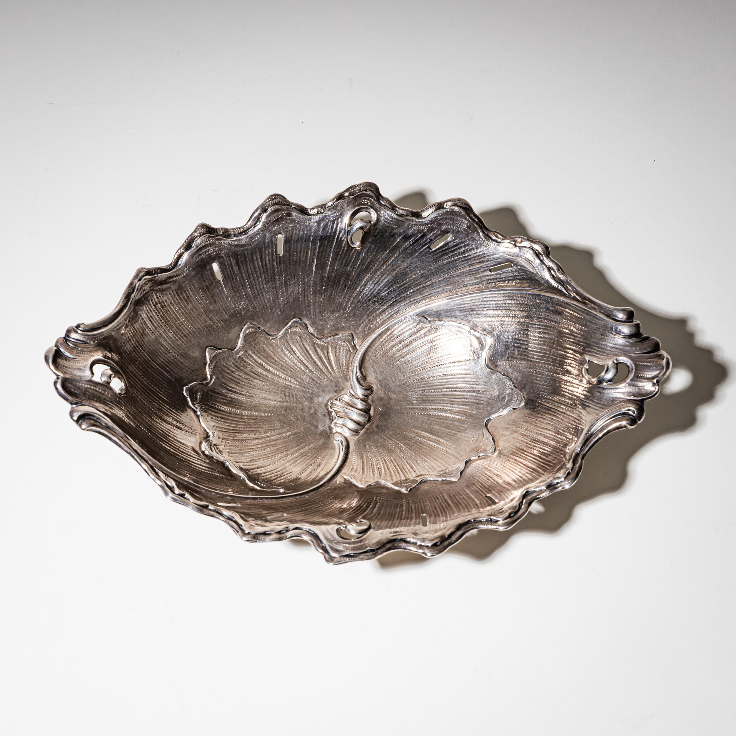 Petit plat en argent finement ouvragé, de forme asymétrique et dynamique, inspiré de motifs de coquillages et de feuilles. Le design fluide confère à la pièce un caractère organique et décoratif. Estampillé avec la marque du fabricant 