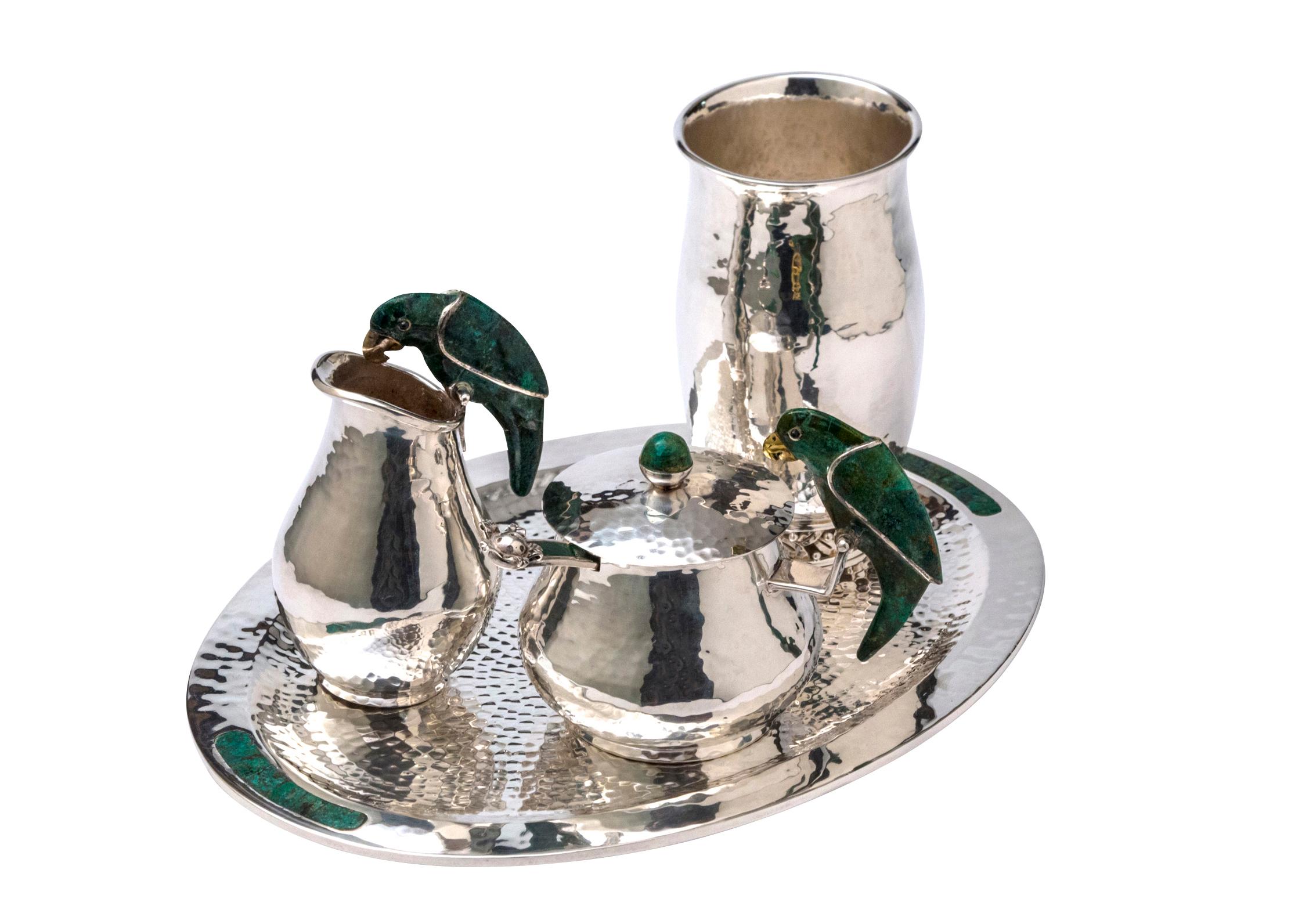 Silver drink service set by Emilia Castillo.

5-piece hammered silver plate Emilia Castillo parrot drink service set with parrot motif at single side handles featuring inlaid green turquoise and brand stamp at undersides. Includes 1 tray (12