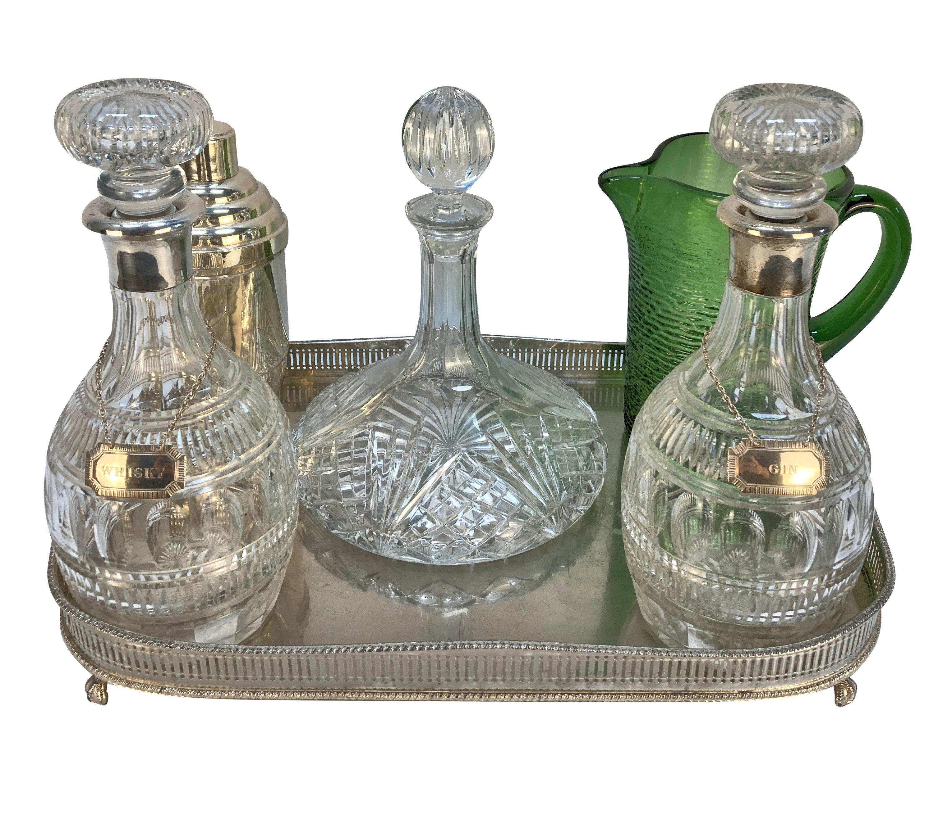 Un plateau à boissons anglais en argent plaqué, supportant une paire de carafes en verre taillé d'Elkington & Co, avec des cols en argent sterling estampillés et datés de 1921 et des étiquettes de boissons. Il y a également un décorateur de bateaux,