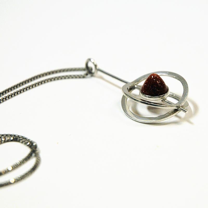 Beautiful vintage silver drop pendant on chain by Elis Kauppi for Kupittaan Kulta, Åbo Finland 1973. In the middle a lovely sand shimmering colored precious stone surrounded by a sprinkle shaped silver pendant. Measures pendant: 5 cm H x 2 cm W x 1