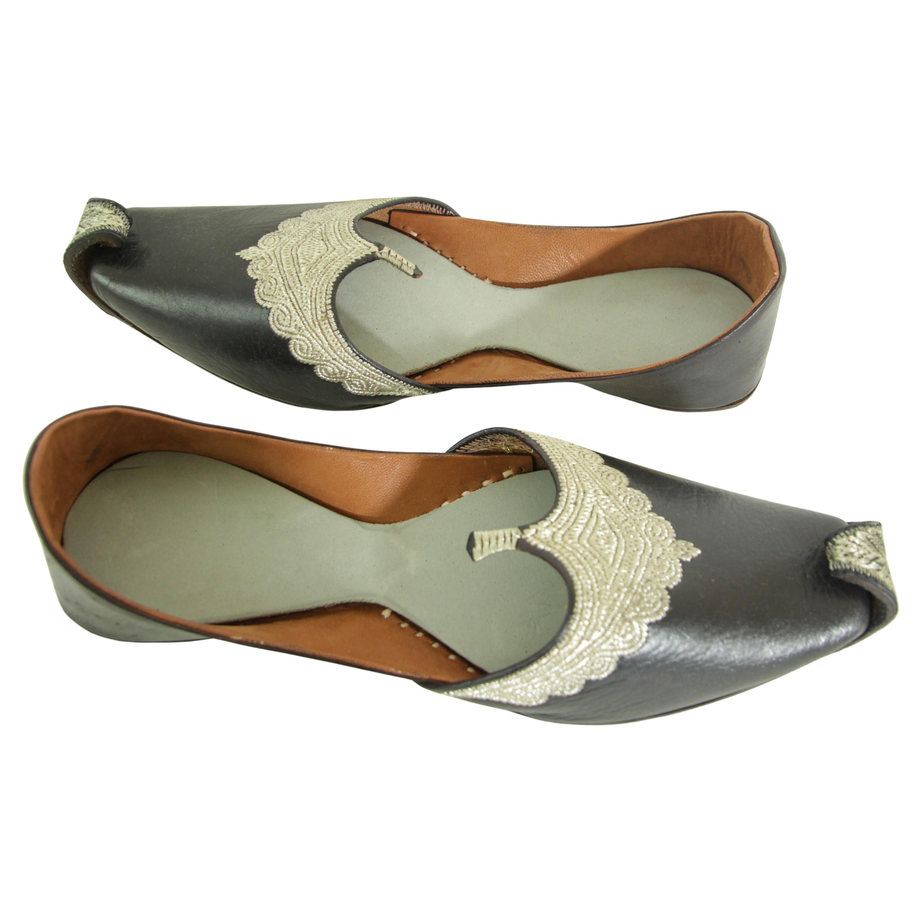 Vintage silver embroidered black leather slippers in Mughal Islamic Rajasthani Shoes.
This is a beautiful pair of Indian Punjabi Jutti shoes made of black leather with silver detailed embroidery with curled up front toes.
This style of Moorish shoes