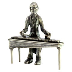 Silver figure of a musician playing the xylophone