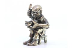 Silver figure of a shoemaker sitting and repairing shoes