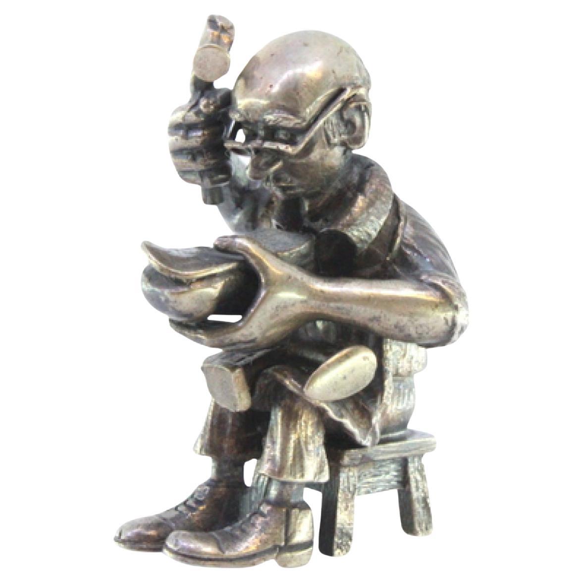 Silver figure of a shoemaker sitting and repairing shoes For Sale